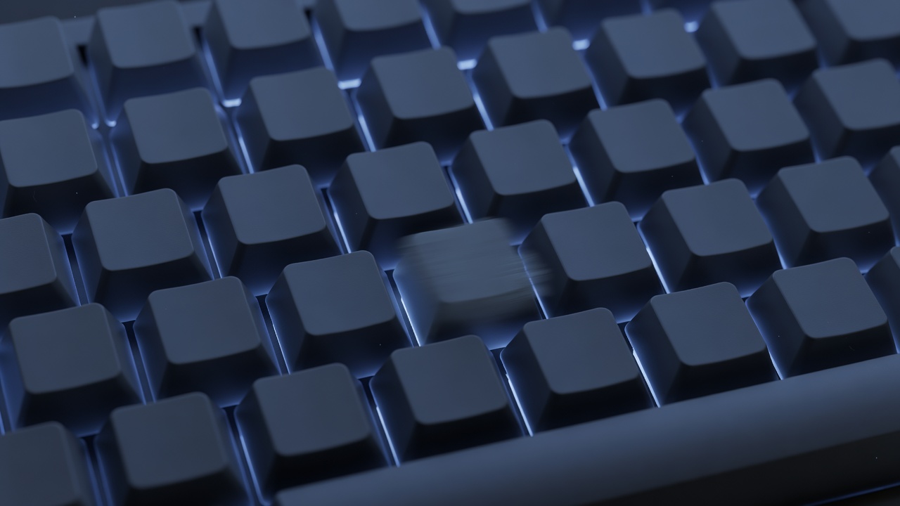 Overhead close-up of a mechanical keyboard with one key struck mid-press, motion-blurred keycap, faint dust motes suspended in cool blue-toned air, backlit rim lighting, wide-angle lens, 1/60s shutter blur.